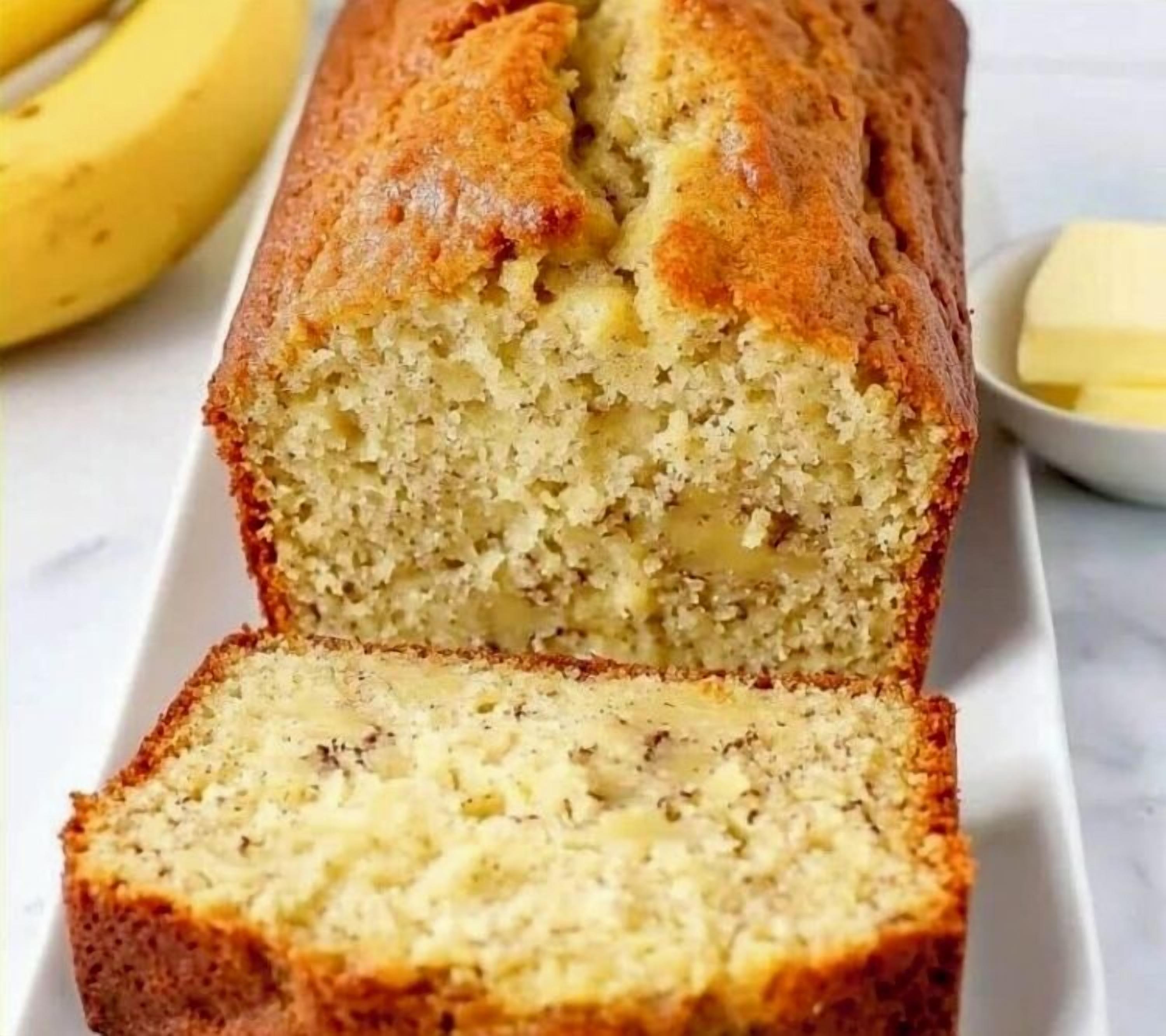 Un pa de banana amb crosta daurada, tallat per dins per mostrar un interior humit.