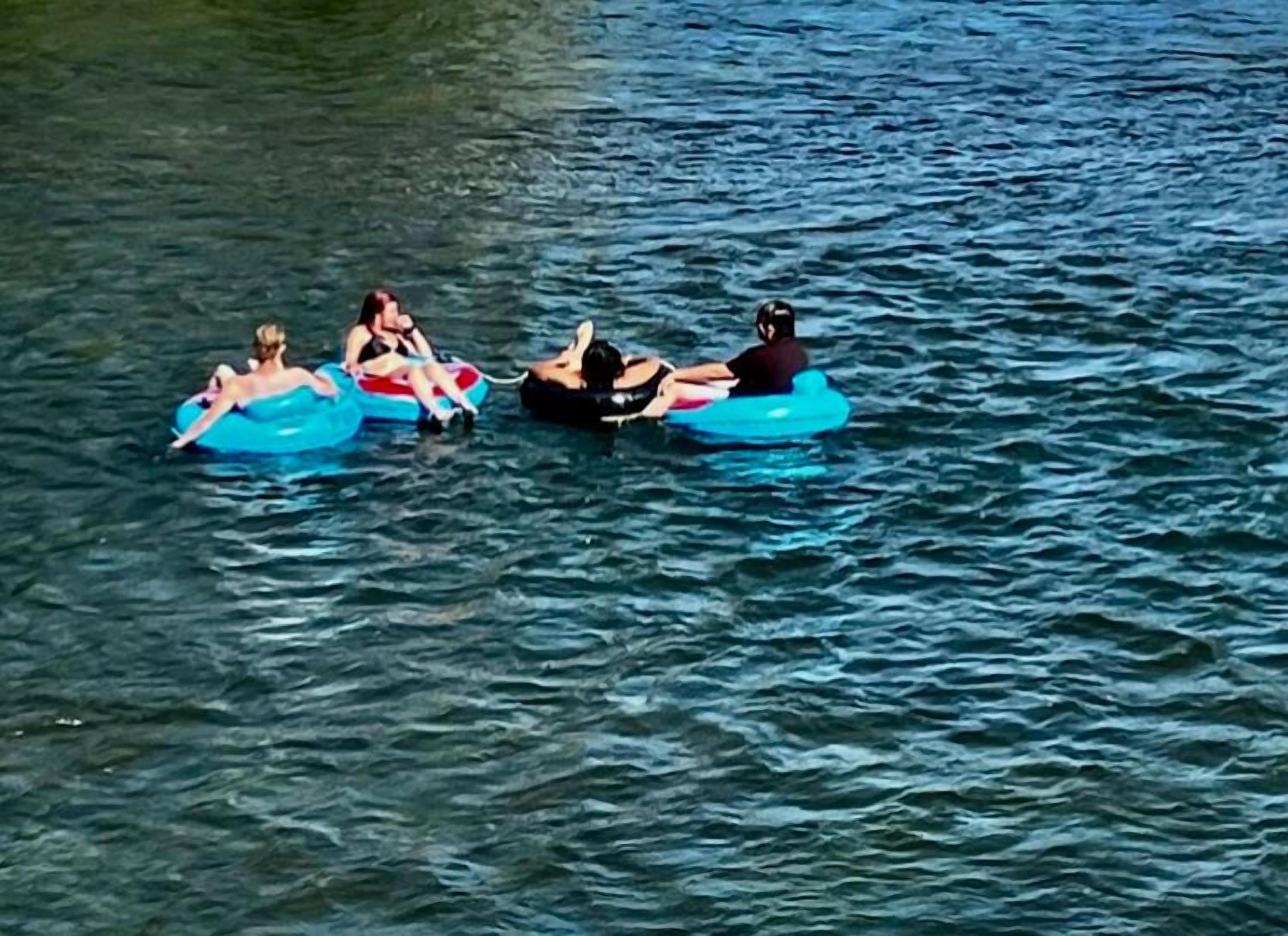 Menschen treiben aufblasbare Liegestühle im Wasser.