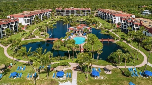 A resort with multiple buildings, a central pool, and surrounding palm trees. - Beautiful Pointe Santo Overlooking Gulf (Sanibel)