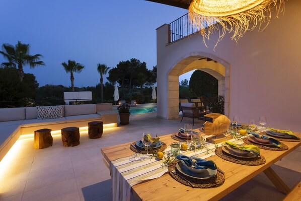 An outdoor dining area with a pool, seating, and a pergola.