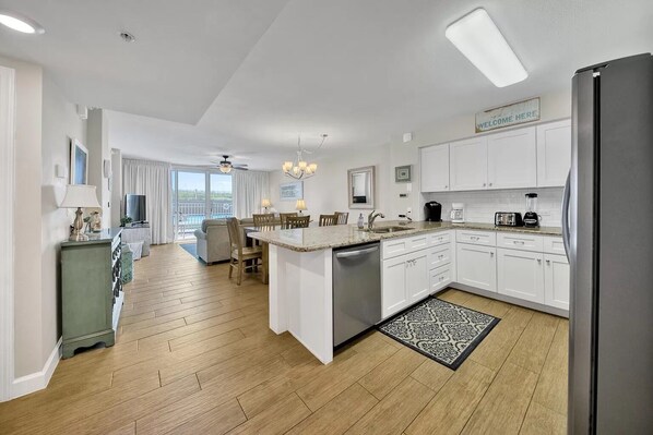 A modern kitchen with white cabinets, a central island, and a dining area with a view.