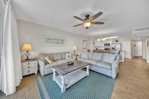 A living room with a sofa, coffee table, and a ceiling fan. - Oceanfront Ground-floor Poolside Private Patio IP107 55 steps to Beach! (Fort Walton Beach)