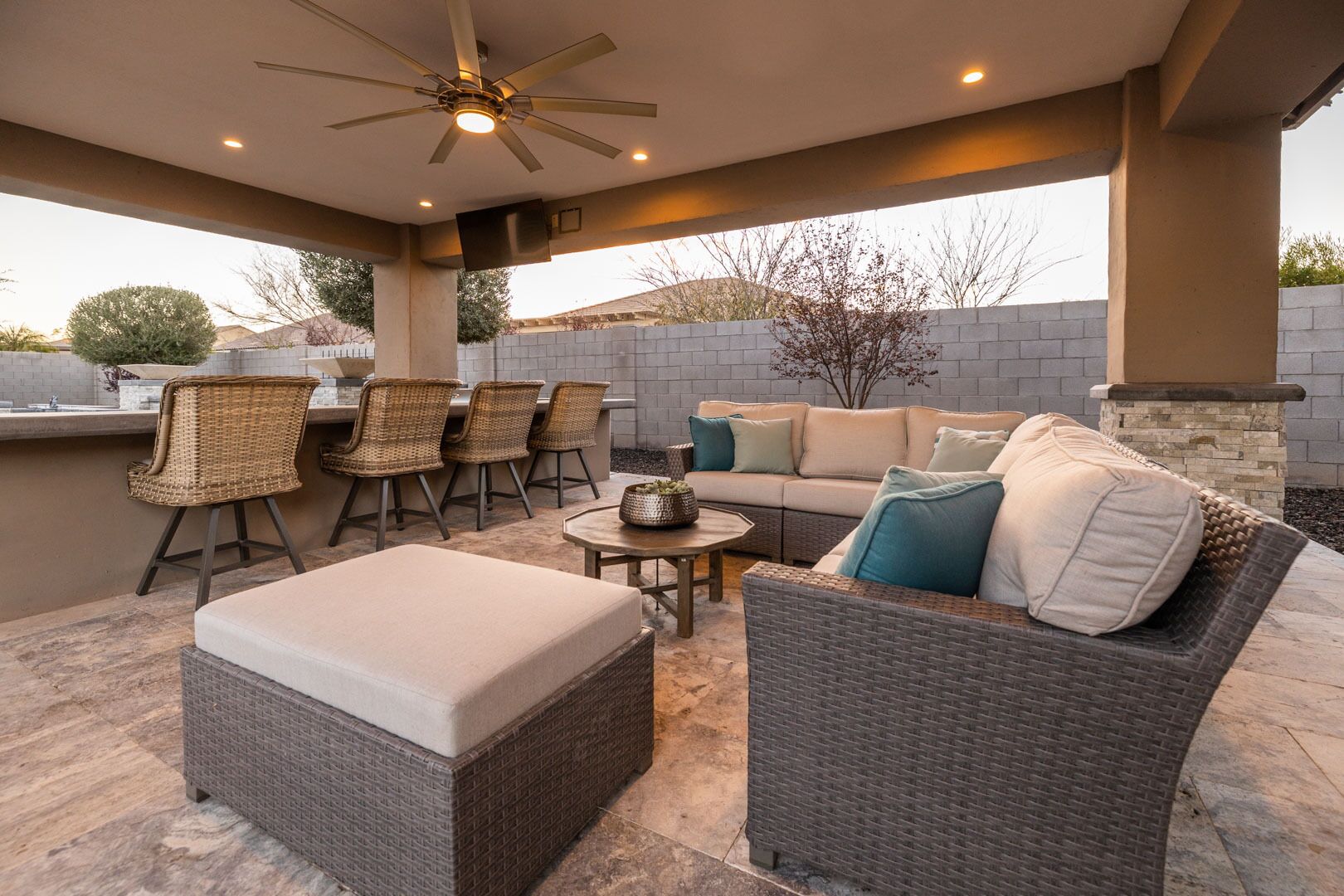 An outdoor patio with wicker furniture, a sofa, and a ceiling fan.