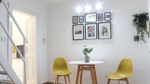 A room with a staircase, a white door, a white table with a potted plant, and two yellow chairs.