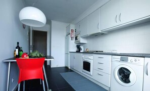 A compact kitchen with white cabinets, a washing machine, and a red chair. - 2Stay - A1 Local Accommodation with swimming pool (Ponta Delgada)