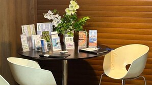 A table with brochures, a vase with flowers, and two white chairs in a room with wooden paneling and a red pendant light. - 2Stay - A1 Local Accommodation with swimming pool (Ponta Delgada)