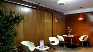 A reception area with a wooden wall, a potted plant, white chairs, a small table with a vase, and a red pendant light. - 2Stay - A1 Local Accommodation with swimming pool (Ponta Delgada)
