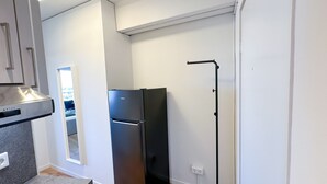 Una cocina moderna con un refrigerador negro, un extractor de acero inoxidable y piso de madera.