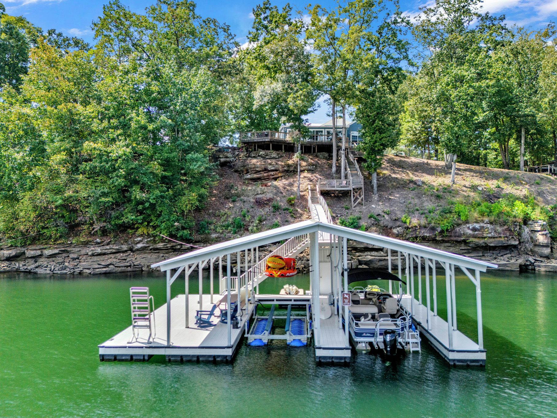 A dock with a covered seating area, a lifeguard stand, and a boat ramp.