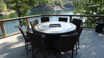 Mesa redonda con sillas sobre una terraza de madera con vistas a un lago.