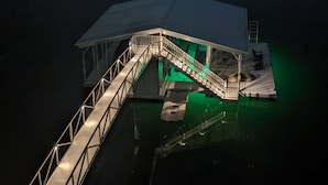 A dock with a covered walkway leading to a boat. - Barney’s Bluff - Towing Pontoon + Dock, Pet-Friendly (Crane Hill)