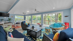 A spacious sunroom with a ceiling fan, large windows, and a variety of seating including a sofa, chairs, and a wicker chair. - Barney’s Bluff - Towing Pontoon + Dock, Pet-Friendly (Crane Hill)