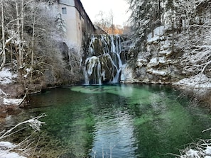 Un paysage naturel avec une cascade, de l’eau claire et des arbres environnants.