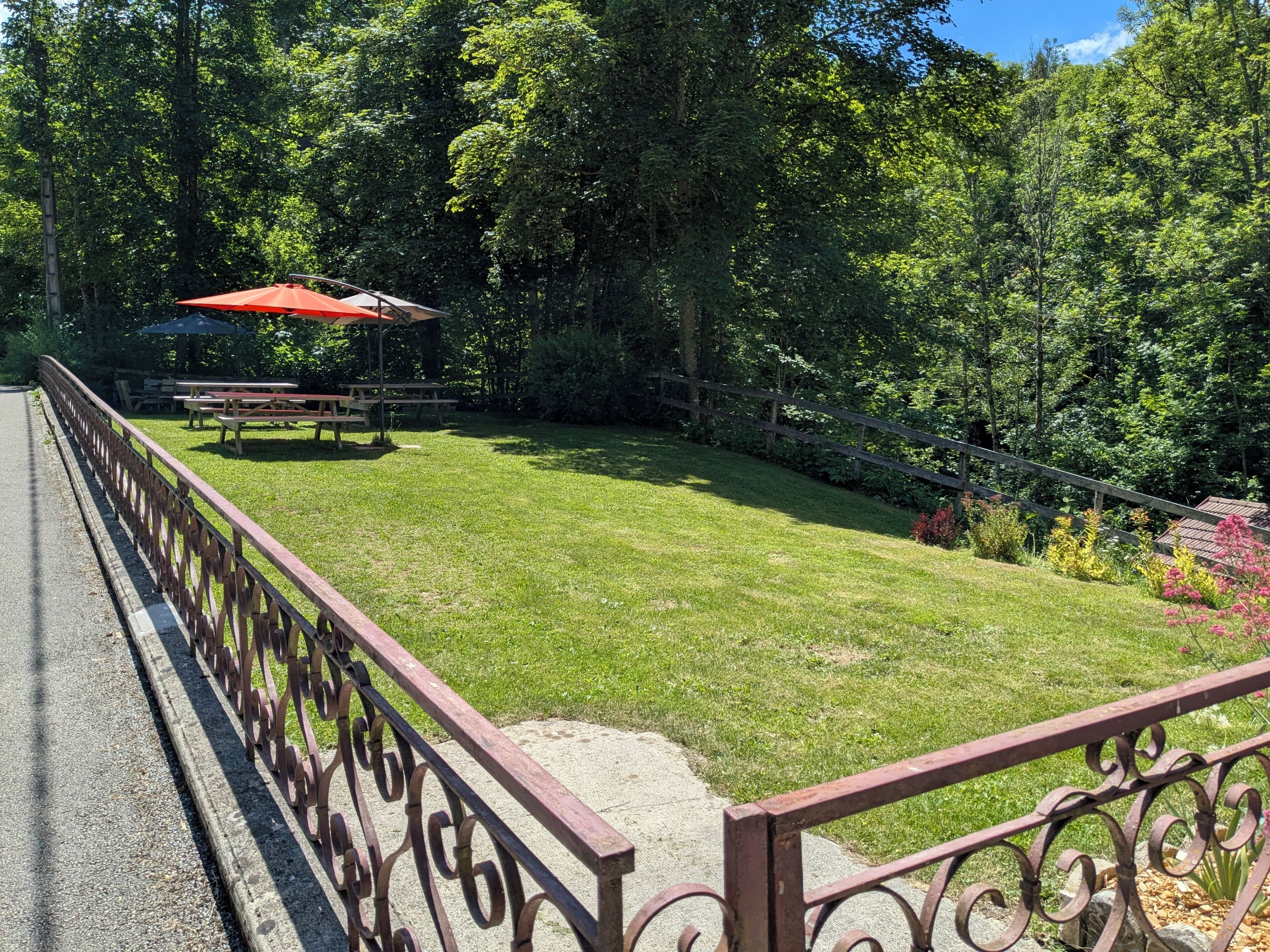 A fenced outdoor area with picnic tables and an umbrella.