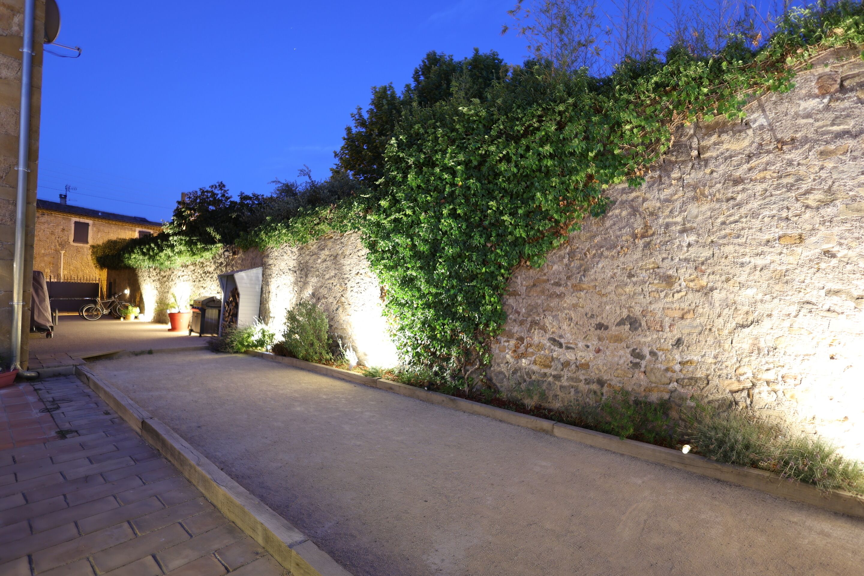 A narrow street with a stone wall on one side and a paved sidewalk on the other.