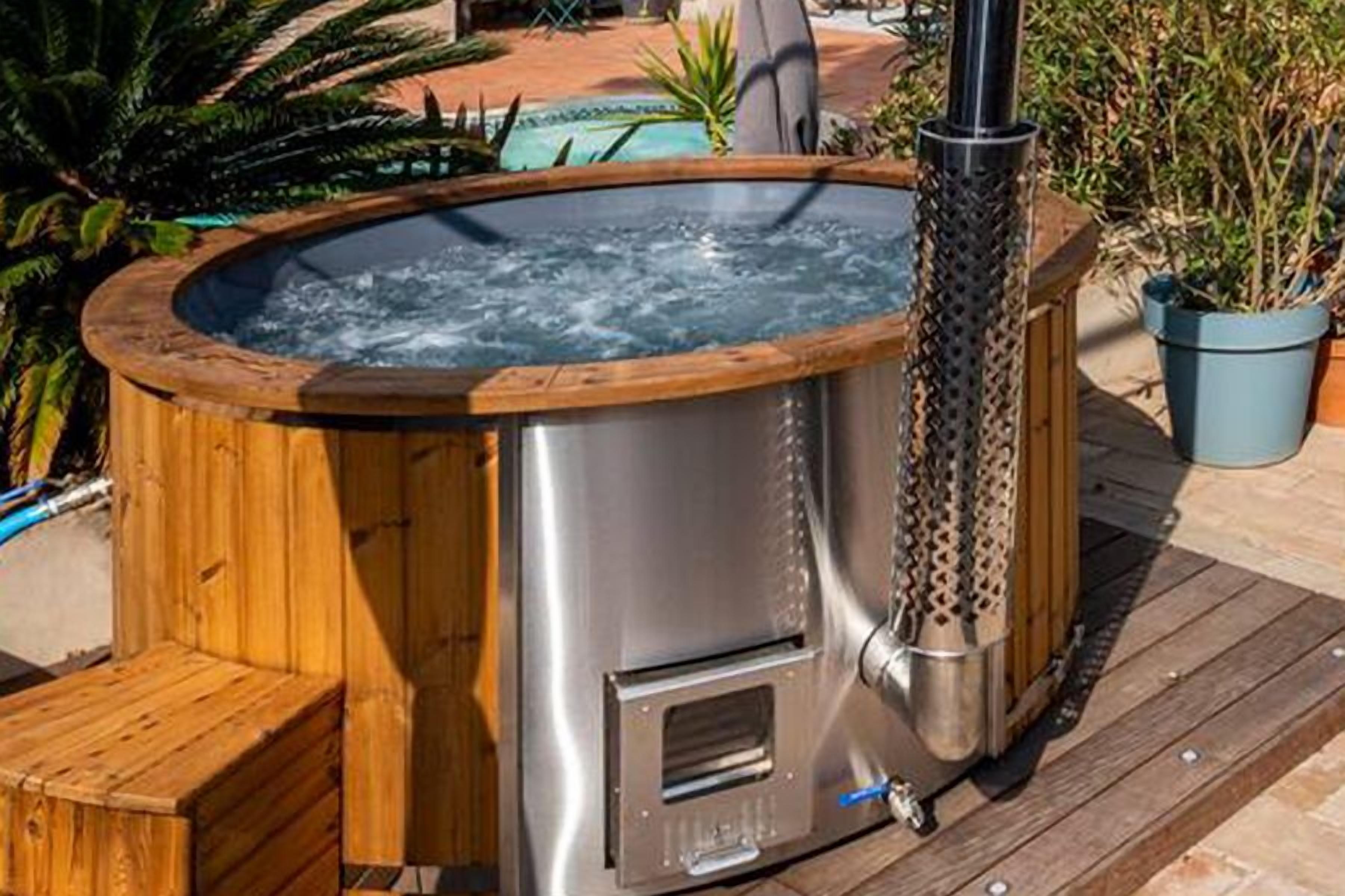Un bain à remous doté d’une structure extérieure en bois et d’un intérieur métallique, installé sur une terrasse en bois.