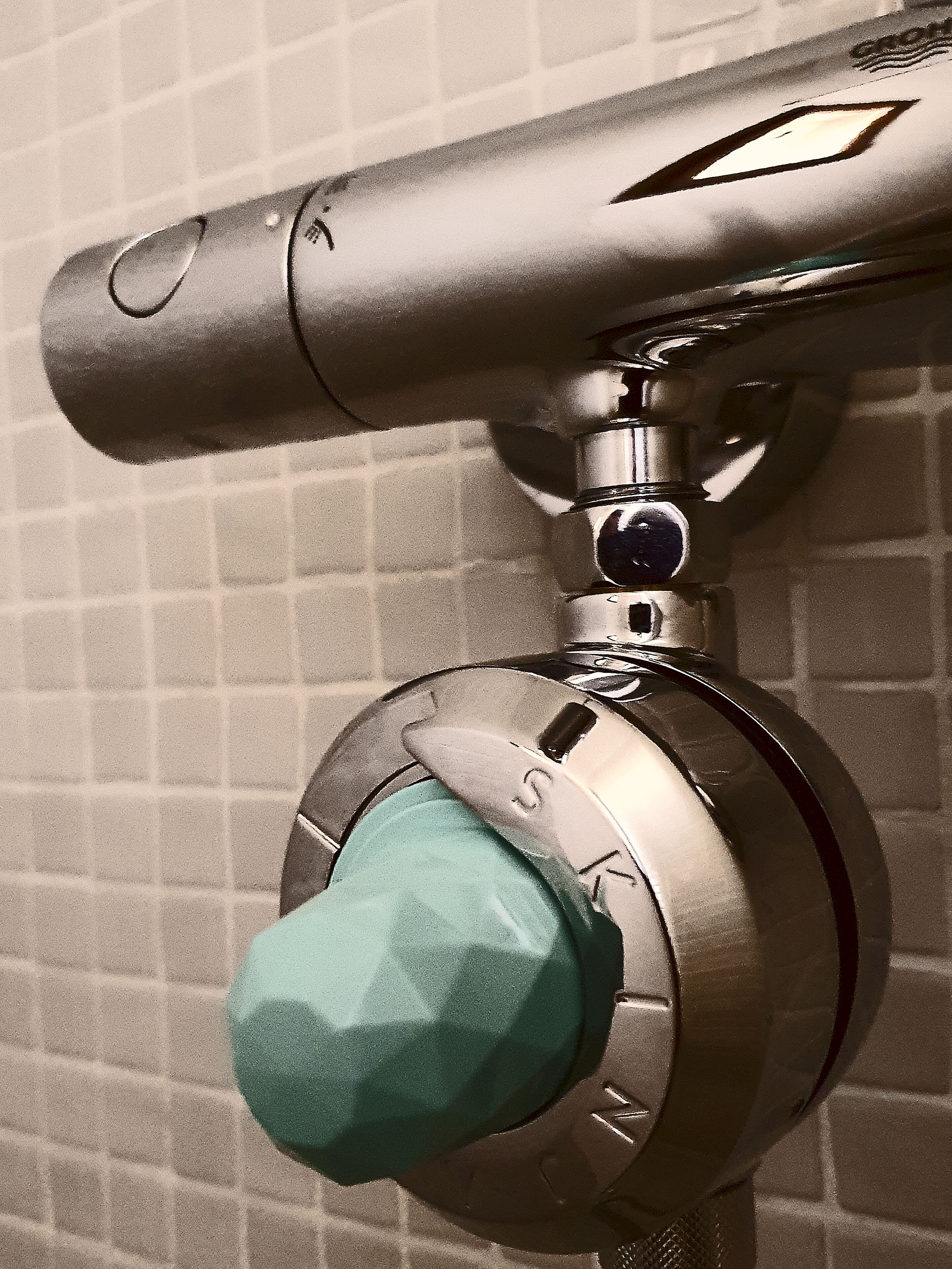 Ein Badezimmerarmaturen-Auslauf mit grünem Hebel und sichtbarem Markenemblem.