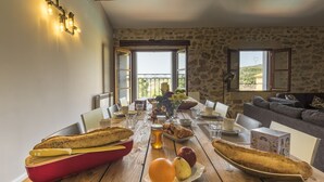A dining table set with bread, fruits, and drinks, overlooking a scenic view. - Maison Dix (Neffies)