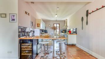 A modern kitchen with a central island, bar stools, and a wine cooler.
