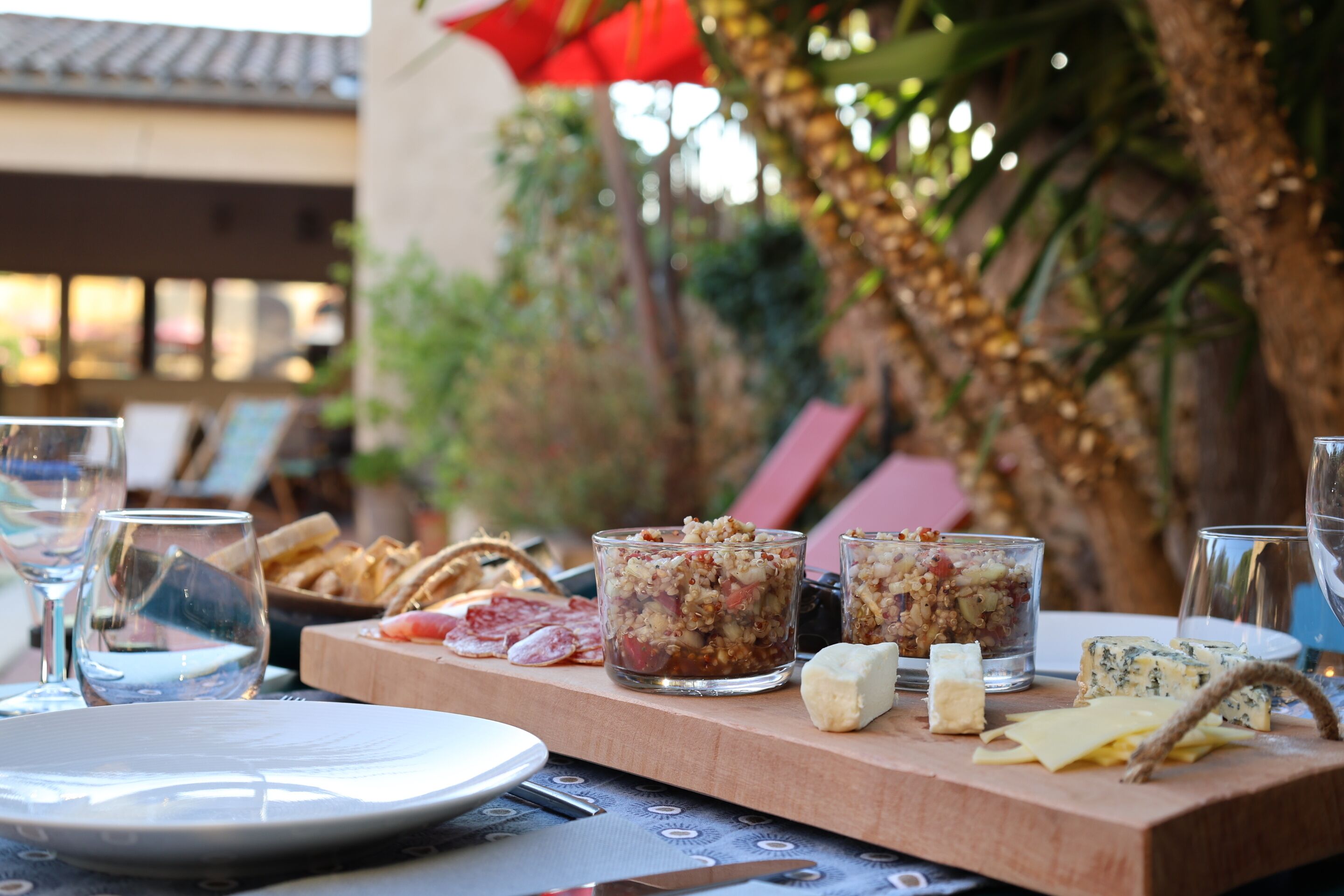 A table set with plates, glasses, and a variety of cheeses and cured meats.