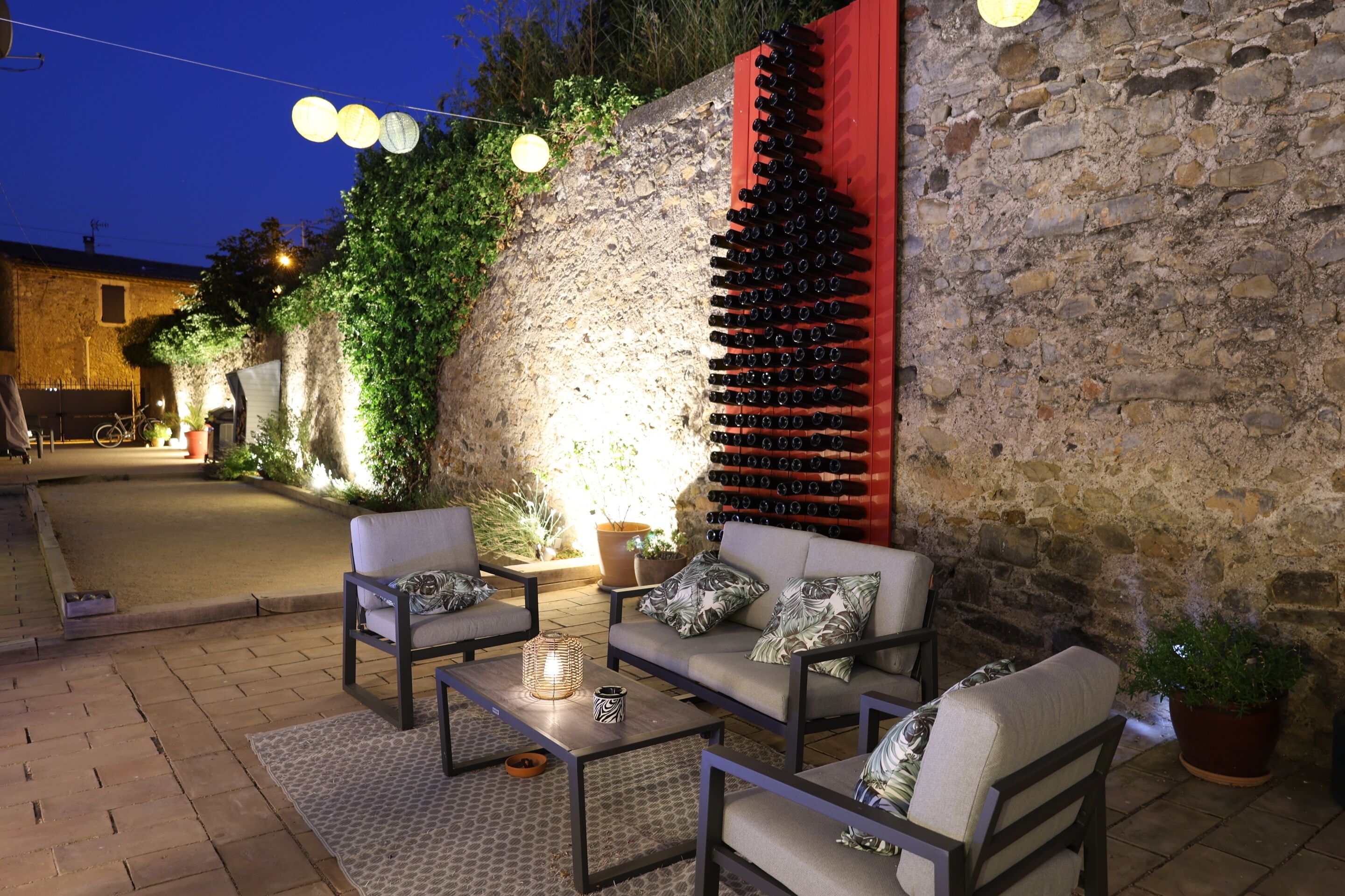 Un espace extérieur aménagé avec un mur en pierre, un meuble à vin et des plantes en pot.