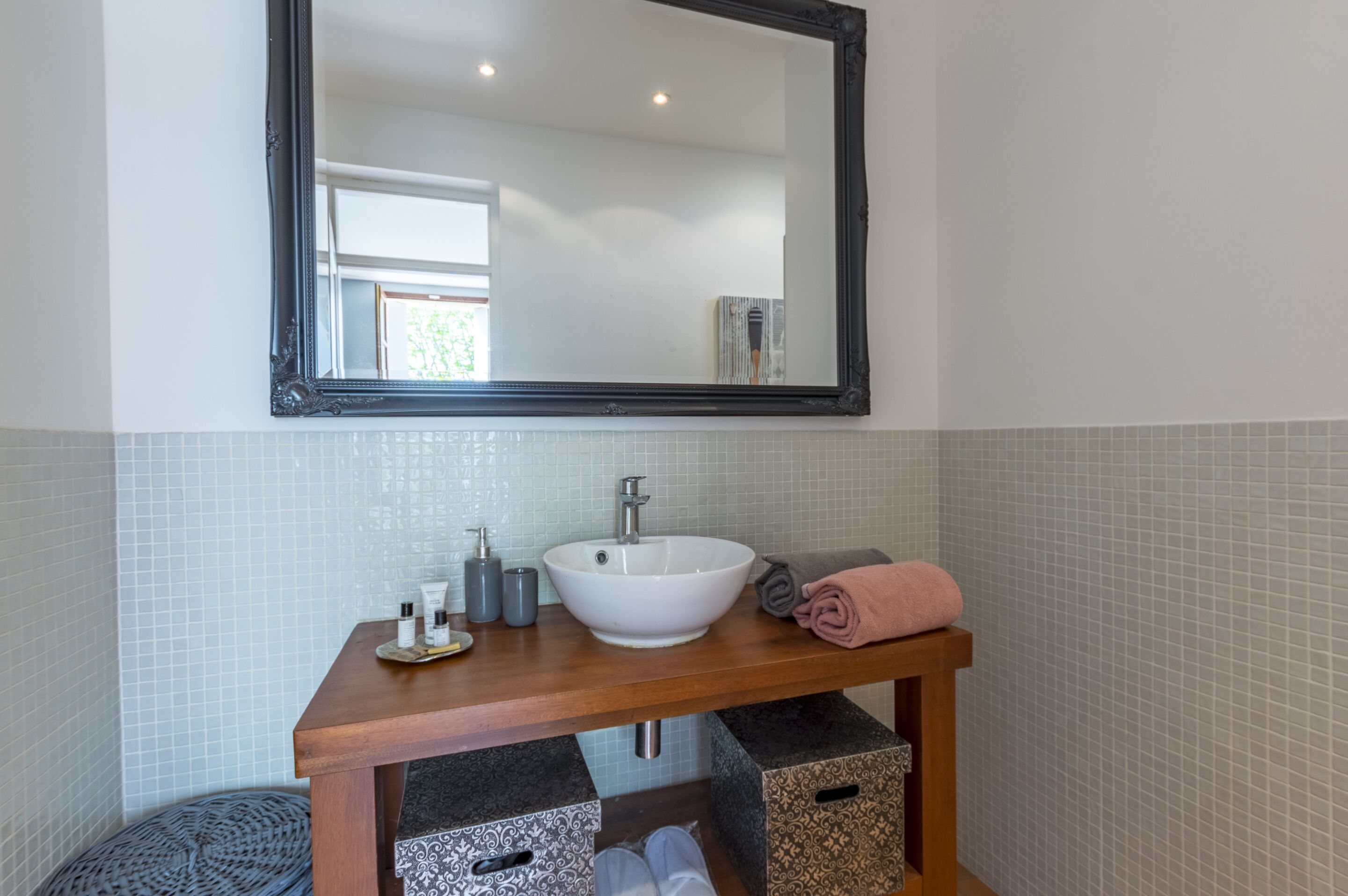 A bathroom with a white sink, a mirror, and storage boxes.