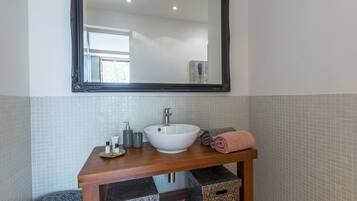 A bathroom with a white sink, a mirror, and storage boxes.