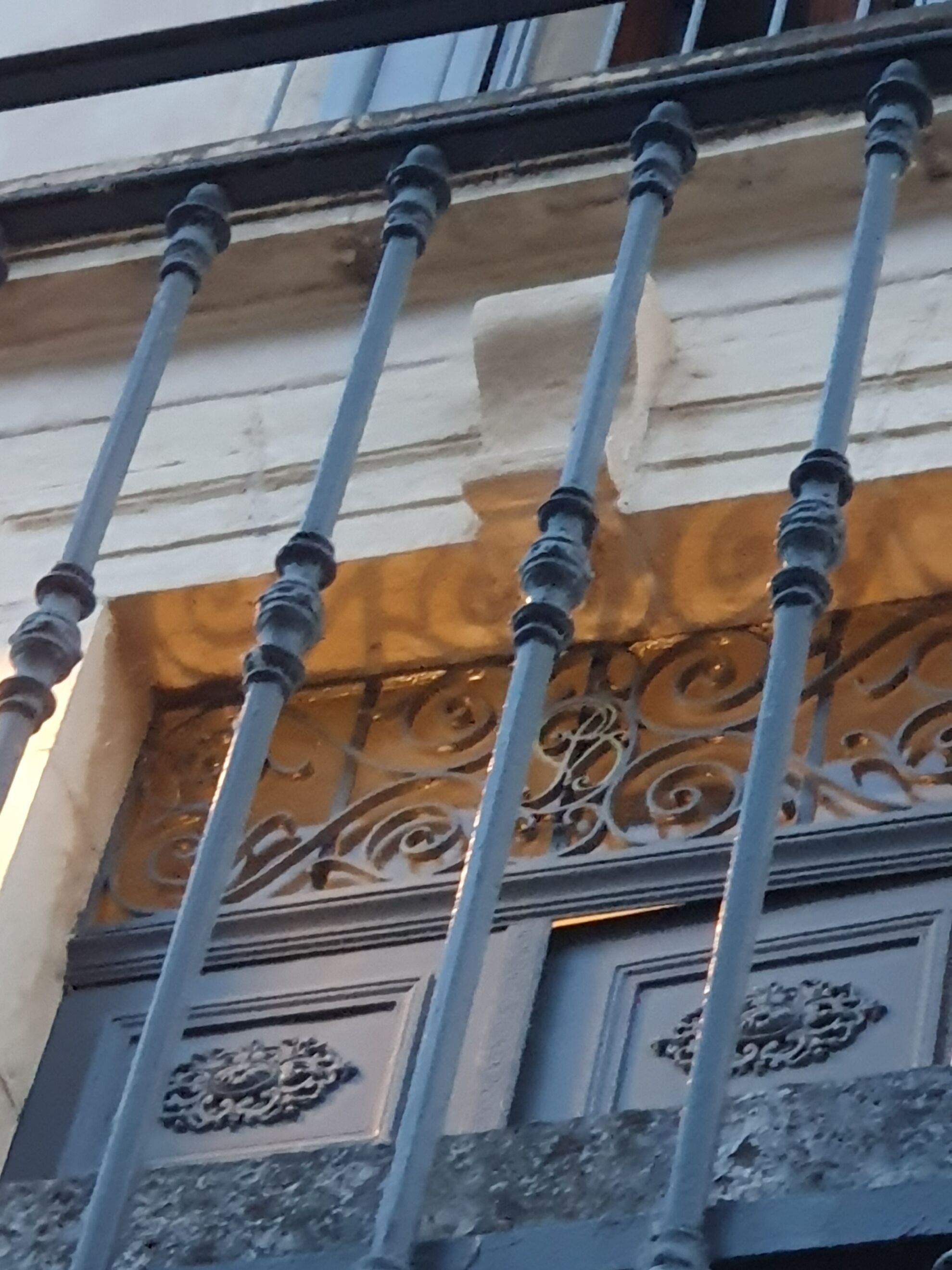Une rambarde en métal ornée de motifs complexes et un panneau décoratif aux motifs élaborés.