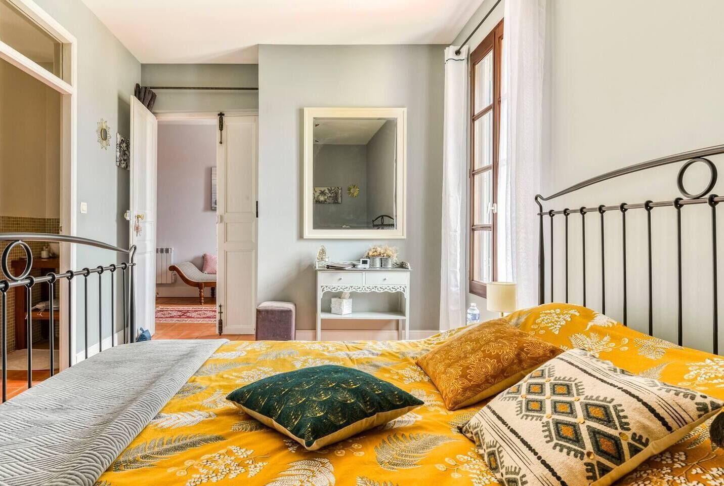 Une chambre à coucher avec un lit, une table de chevet, un miroir et une armoire.