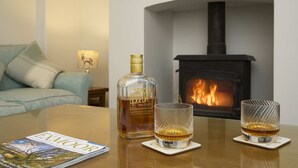 Una botella de Stagecoach Breakwater sobre una mesa con dos vasos de whisky. Se ve una chimenea al fondo.