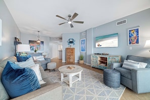 A living room with a grey sofa, a round coffee table, and a ceiling fan.