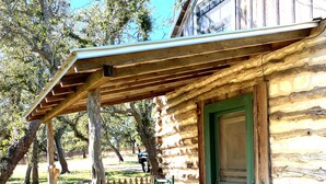 A rustic log cabin with a covered porch and a green door.