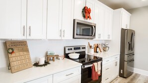 Une cuisine moderne avec des armoires blanches, des appareils en acier inoxydable et un sol à motifs écossais.