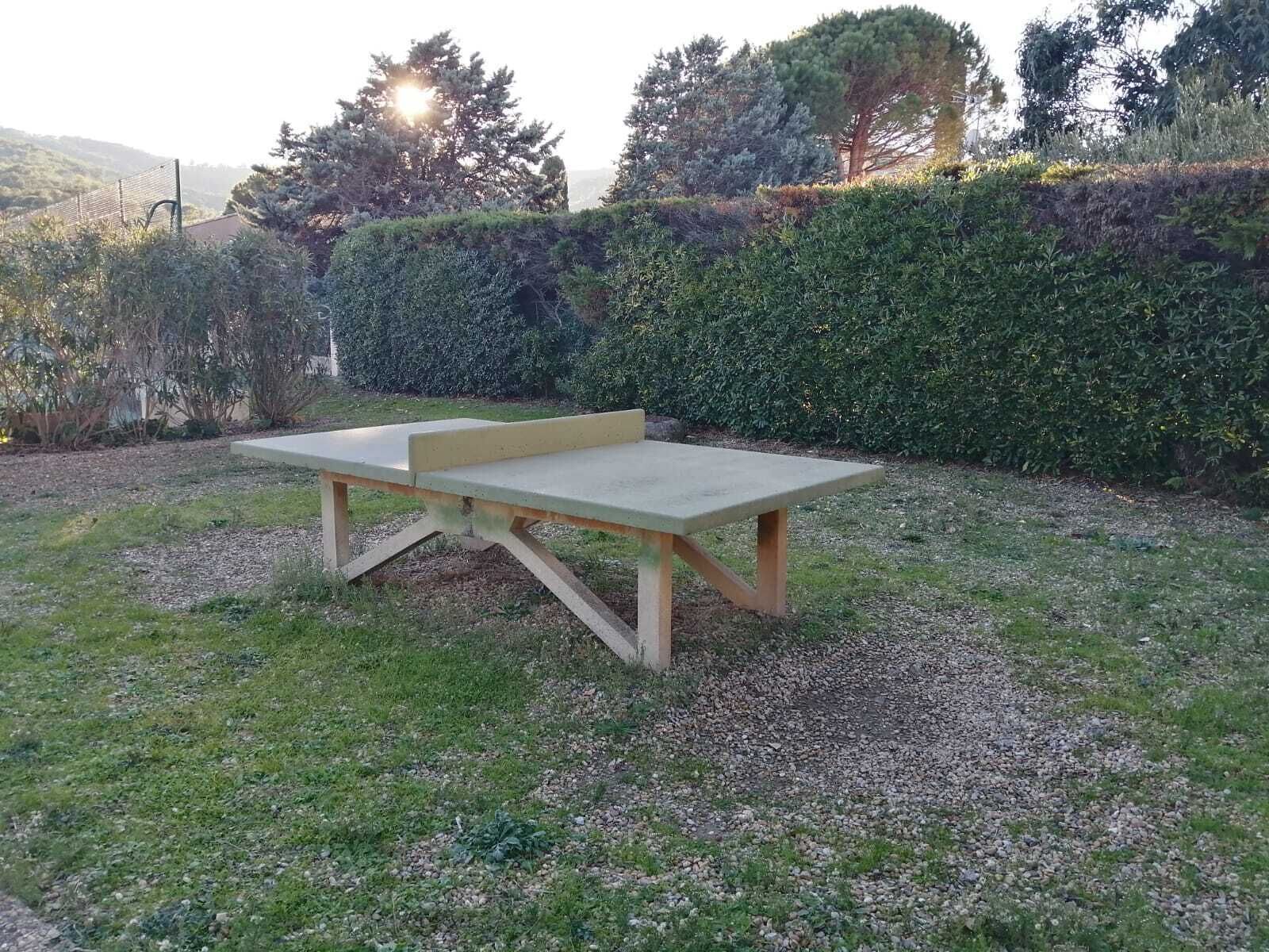 A concrete picnic table with a bench in a grassy outdoor area.