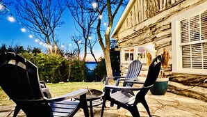 A patio with Adirondack chairs and a fire pit, overlooking a stone building with a view of the water. - The Best Little Shorehouse in Texas (Volente)