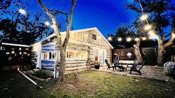 Guests can enjoy outdoor dining and socializing on the porch, surrounded by a well-maintained lawn and trees.