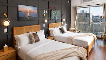 A hotel room with two beds, a large window with a city view, and wall-mounted artwork.
