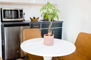 A kitchen with a microwave, a sink, and a potted plant on a white table. - The Modernist Hotel (Long Island City)