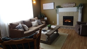 A cozy living room with a fireplace, a sofa, a coffee table, and a chair. - Turkey Creek Retreats  (Belfry)