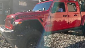 A red Jeep Wrangler with 'MOJAVE' written on the side, parked on gravel with a house in the background. - Turkey Creek Retreats  (Belfry)