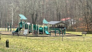 A playground with green equipment and a covered seating area. - Turkey Creek Retreats  (Belfry)