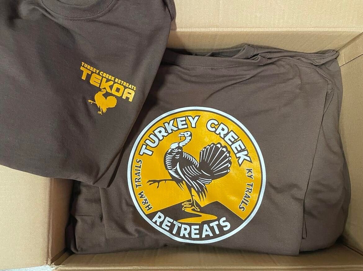 En brun t-shirt med en logotyp och texten "Turkey Creek Retreats".