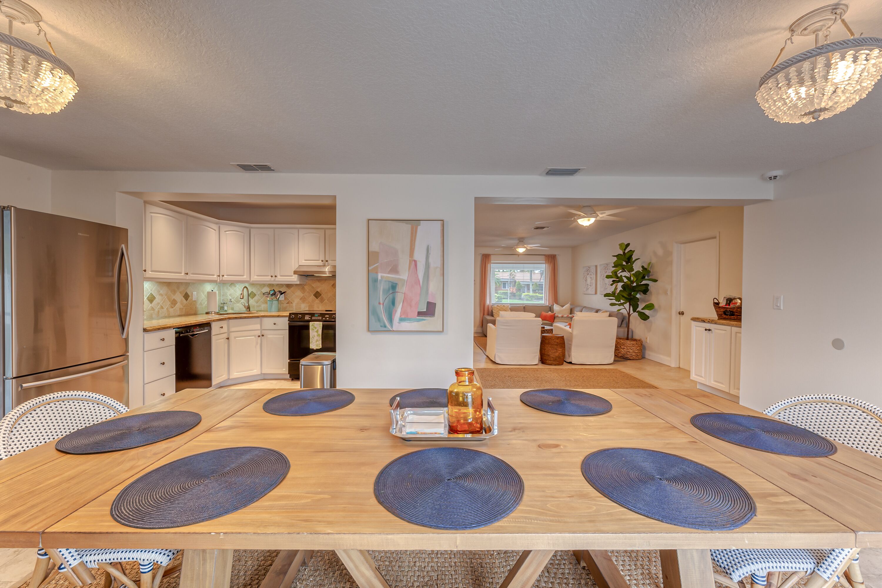 A spacious dining area with a wooden table, blue placemats, and a central decorative item.