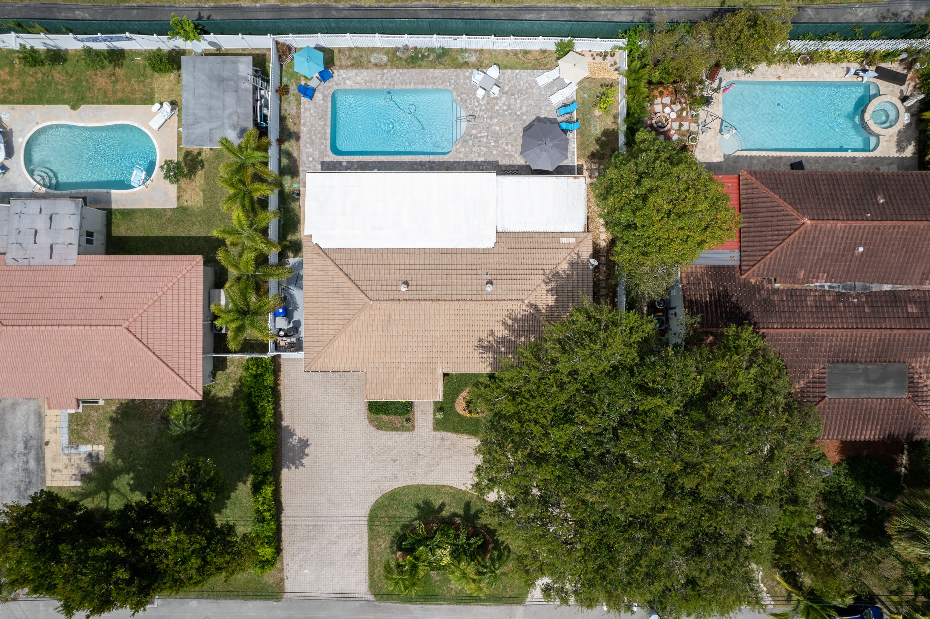 Vista aérea de una propiedad residencial con dos piscinas, un patio cubierto y un jardín ajardinado.