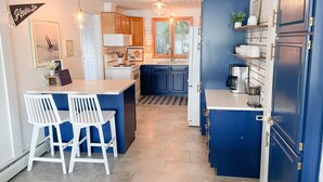 A modern kitchen with a central island, white bar stools, and a blue accent wall.