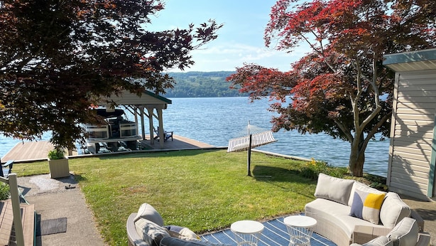 A patio with outdoor furniture, a hammock, and a view of a lake.
