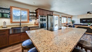 Una cocina con encimeras de granito, electrodomésticos de acero inoxidable, armarios de madera y una isla grande con taburetes de bar.