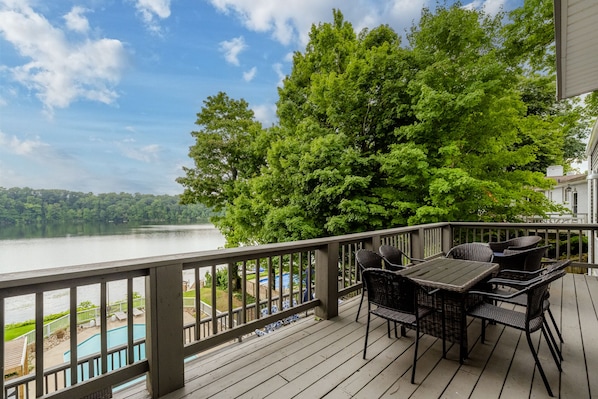 Une terrasse en bois, agréée de mobilier d’extérieur, qui offre une vue sur un lac et une piscine.