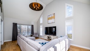 A spacious living room with a large sectional sofa, a flat-screen TV, and a pendant light.