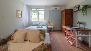 A bedroom with a bed, a small table, and a desk with chairs. - Studio Garden, cozy and unique (SC)